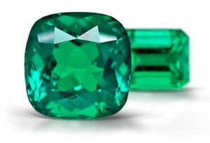 sparkling natural cushion emerald showing light performance and brilliance with another emerald shaped green emerald behind it