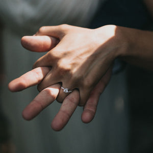 couple holding hands with woman wearing engagement ring