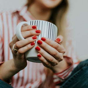 woman wearing modern engagement rings holding coffee cup